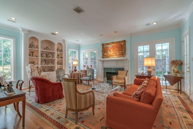 living room featuring healthy amount of natural light, a fireplace, light wood finished floors, ornamental molding, and recessed lighting