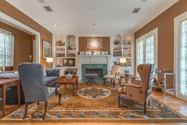 living area with built in features, plenty of natural light, a fireplace with flush hearth, ornamental molding, and recessed lighting