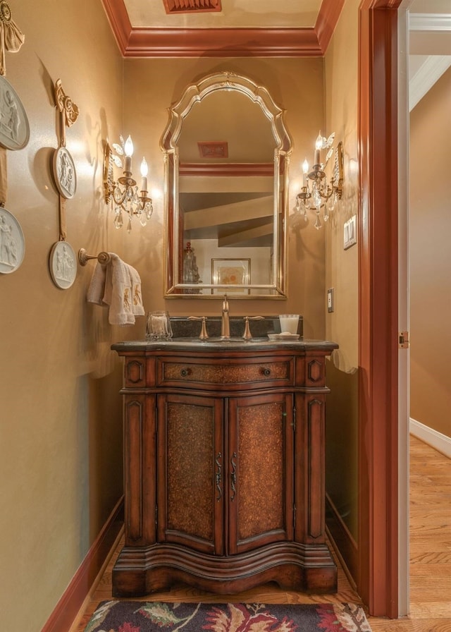 bathroom featuring crown molding, wood finished floors, vanity, and baseboards