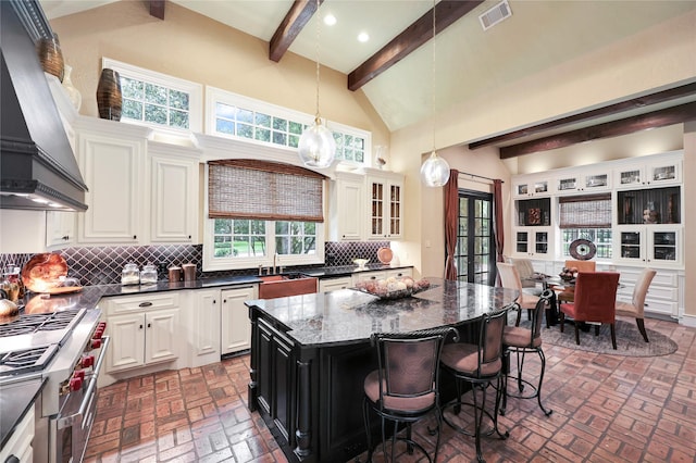 13315 Timberwild Ct, Tomball, TX 77375 - kitchen featuring brick floors, custom exhaust hood, range with two ovens, backsplash, and beam ceiling