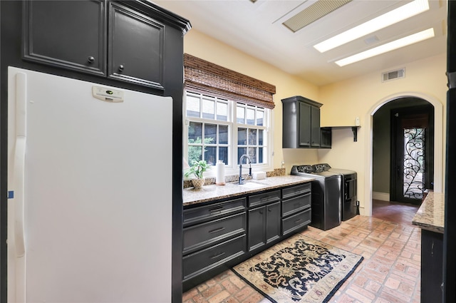13315 Timberwild Ct, Tomball, TX 77375 - kitchen with freestanding refrigerator, independent washer and dryer, arched walkways, a sink, and brick floors