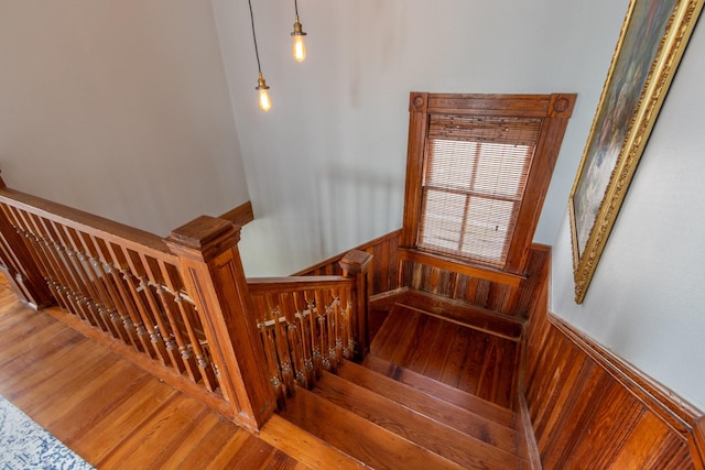 stairs with wood finished floors, a wainscoted wall, and wooden walls