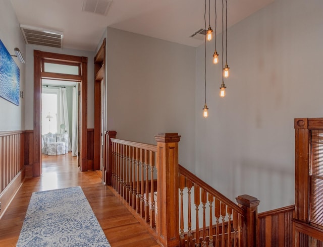 corridor featuring an upstairs landing, wainscoting, and wood finished floors