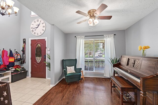 foyer featuring a chandelier, a textured ceiling, ceiling fan, light wood finished floors, and baseboards