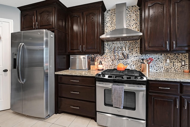 kitchen with stainless steel appliances, wall chimney exhaust hood, decorative backsplash, light tile patterned flooring, and light stone counters
