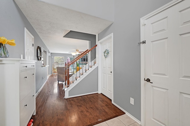 corridor featuring stairs, baseboards, and wood finished floors
