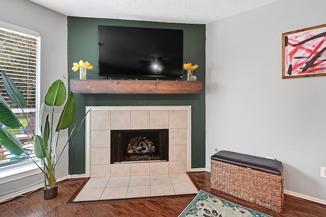 detailed view of a tile fireplace, wood finished floors, and baseboards