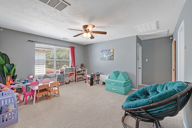 playroom with carpet floors, ceiling fan, attic access, and a textured ceiling