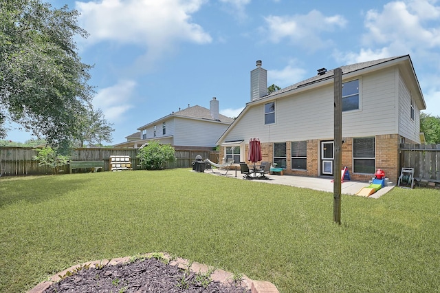 rear view of property with brick siding, a patio, and a chimney