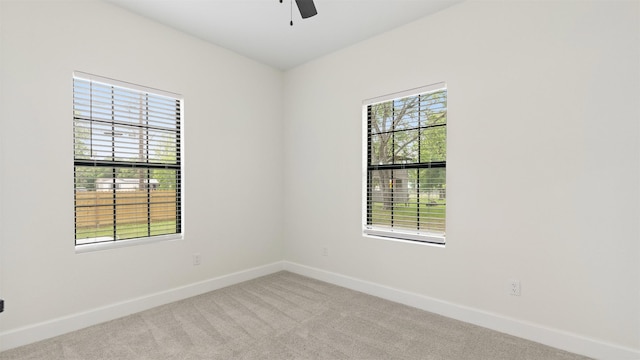 carpeted spare room featuring plenty of natural light, baseboards, and ceiling fan