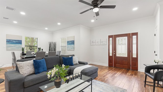 living room featuring wood finished floors, recessed lighting, ornamental molding, ceiling fan, and baseboards