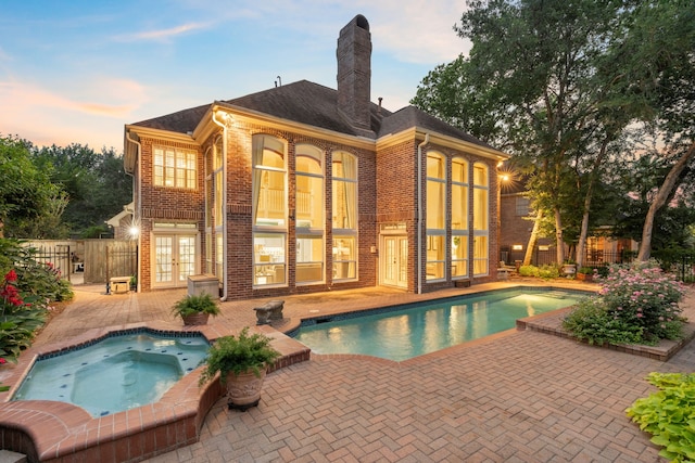 7403 Timberlake Dr, Sugar Land, TX 77479 - back of property at dusk with french doors, an in-ground hot tub, brick siding, a patio, and a chimney