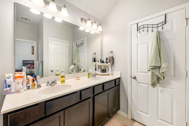 bathroom with double vanity, tile patterned floors, baseboards, and connected bathroom