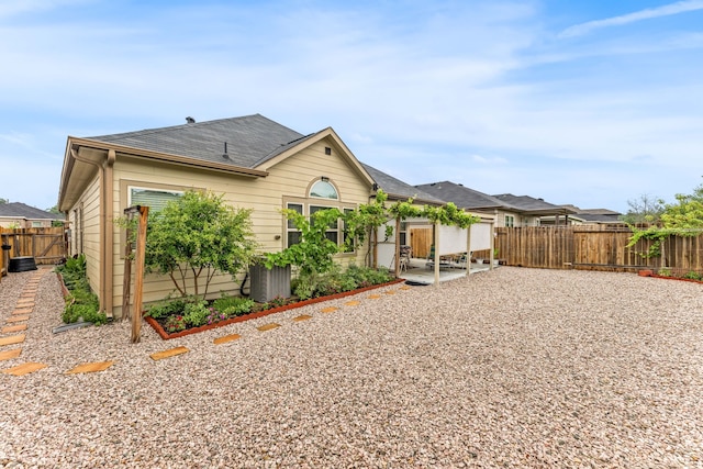 back of property with a fenced backyard, a patio, and roof with shingles