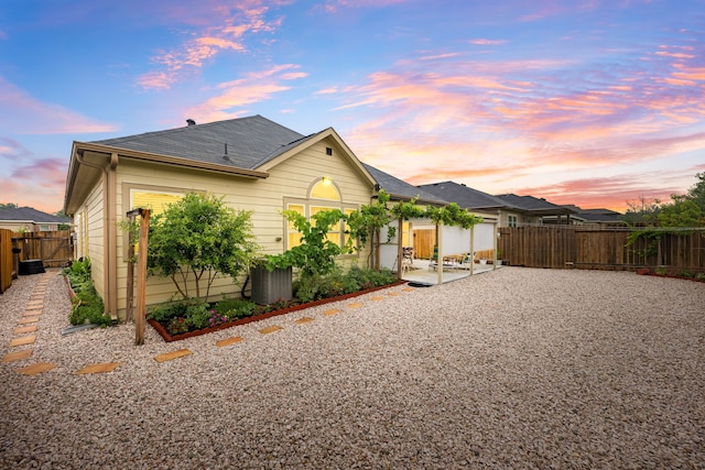 back of property featuring a fenced backyard and a shingled roof