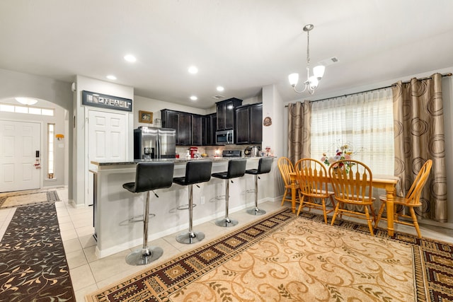 kitchen featuring stainless steel appliances, a chandelier, a breakfast bar area, a peninsula, and light tile patterned floors
