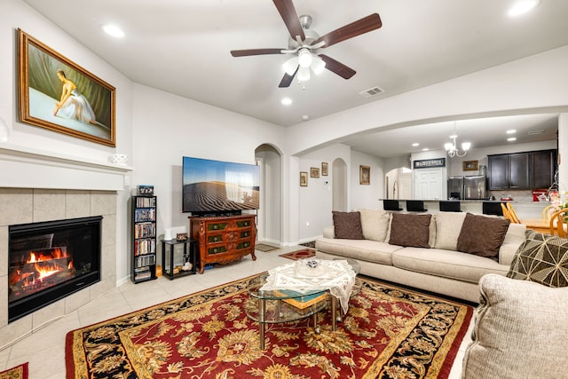living room with arched walkways, recessed lighting, ceiling fan, light tile patterned floors, and a tile fireplace