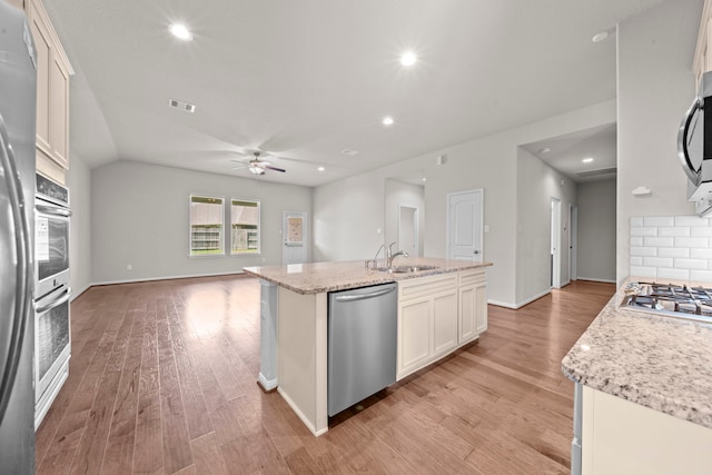 15423 Hopkins Cedar Dr, Humble, TX 77346 - kitchen featuring appliances with stainless steel finishes, a sink, ceiling fan, open floor plan, and light wood-style flooring