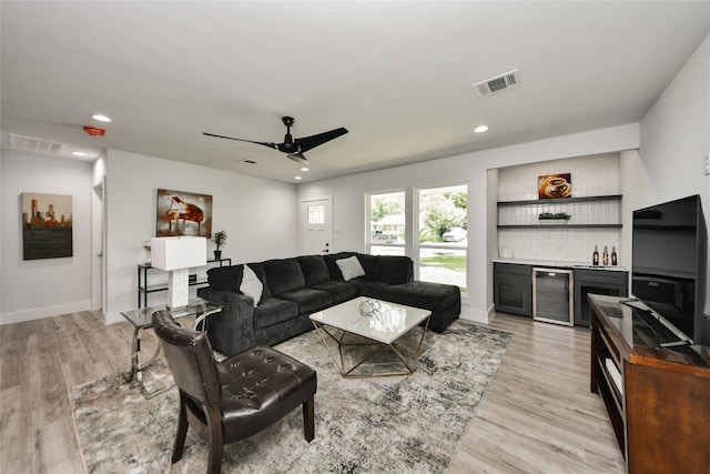 living room featuring a bar, light wood-type flooring, a ceiling fan, wine cooler, and recessed lighting