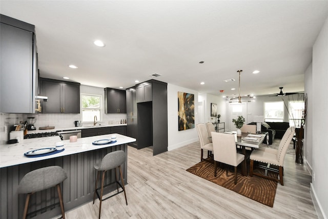 kitchen with baseboards, a peninsula, recessed lighting, light wood-style flooring, and light stone countertops