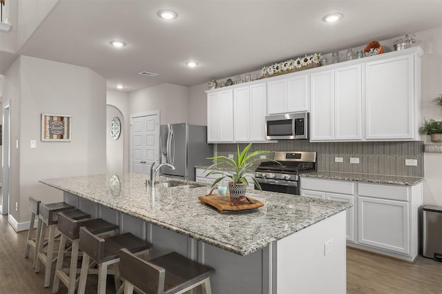 2510 Ocean Key Dr, Texas City, TX 77568 - kitchen with stainless steel appliances, a sink, wood finished floors, an island with sink, and white cabinetry