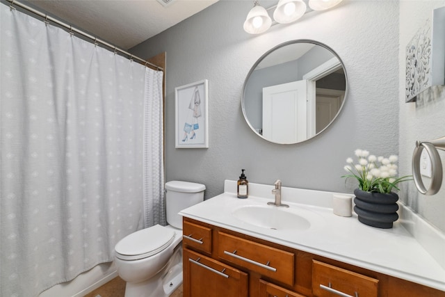full bath featuring toilet, vanity, and a textured wall