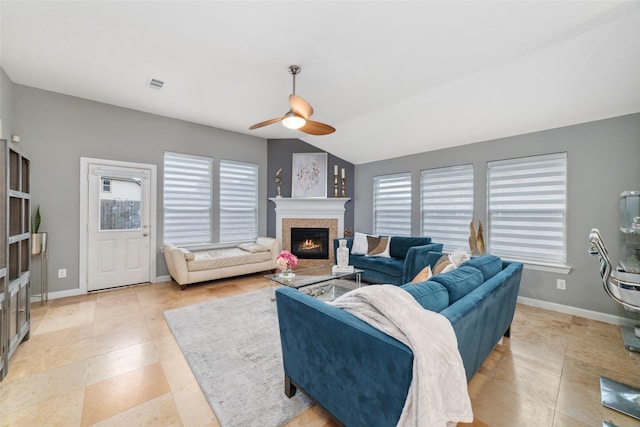 living room with a warm lit fireplace, a ceiling fan, healthy amount of natural light, and light tile patterned floors