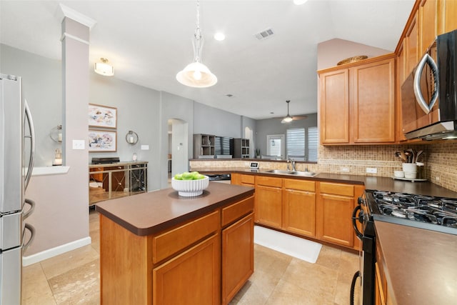 kitchen featuring appliances with stainless steel finishes, a sink, backsplash, arched walkways, and a kitchen island