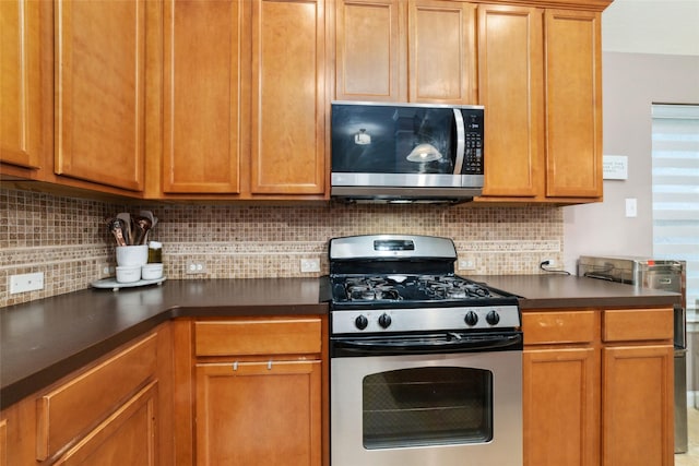 kitchen with stainless steel appliances, dark countertops, and tasteful backsplash
