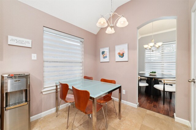 dining space with a chandelier, arched walkways, lofted ceiling, tile patterned flooring, and baseboards