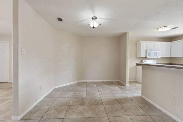 unfurnished dining area with a textured ceiling, light tile patterned floors, and baseboards