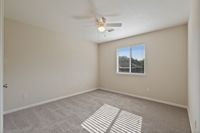 empty room featuring carpet, ceiling fan, a textured ceiling, and baseboards