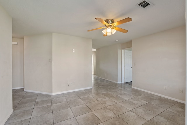 empty room featuring a ceiling fan, light tile patterned flooring, and baseboards
