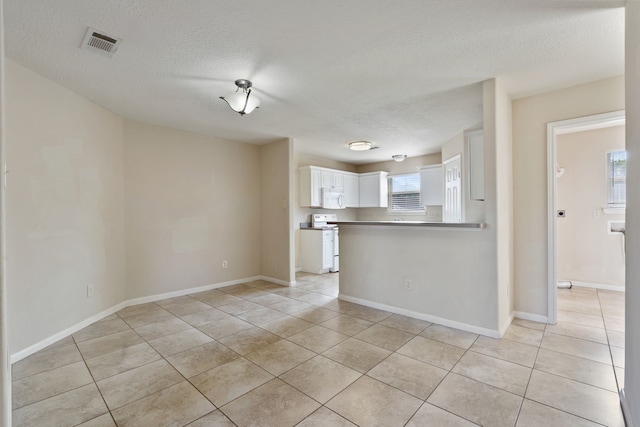 unfurnished living room featuring light tile patterned floors, a textured ceiling, and baseboards