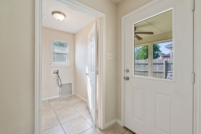 doorway to outside with healthy amount of natural light, ceiling fan, light tile patterned floors, and baseboards