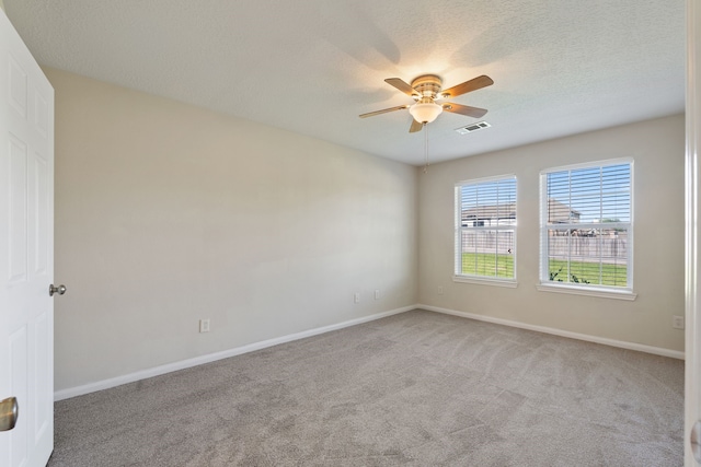 carpeted spare room with a ceiling fan, baseboards, and a textured ceiling