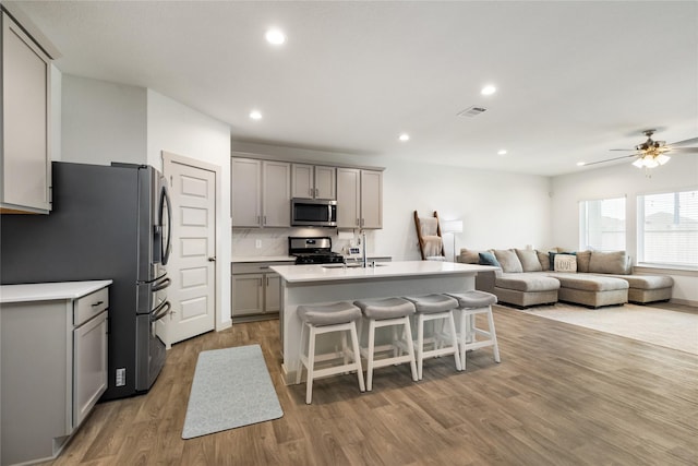 502 Rain Cloud Dr, Baytown, TX 77523 - kitchen featuring gray cabinets, stainless steel appliances, open floor plan, a sink, and a breakfast bar