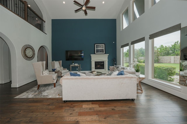 5502 Charlton Ridge Ln, Fulshear, TX 77441 - living area with high vaulted ceiling, a ceiling fan, a glass covered fireplace, wood-type flooring, and arched walkways