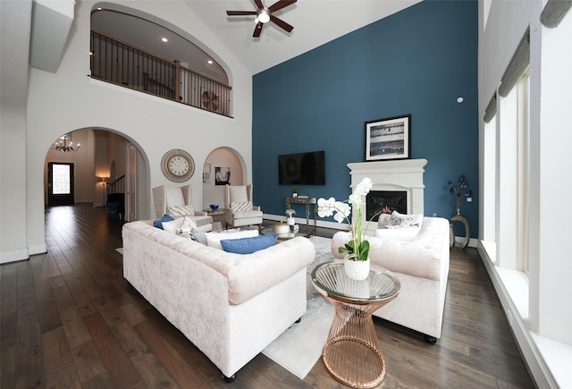 5502 Charlton Ridge Ln, Fulshear, TX 77441 - living room with high vaulted ceiling, arched walkways, a glass covered fireplace, ceiling fan, and dark wood-type flooring