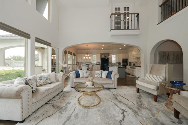 5502 Charlton Ridge Ln, Fulshear, TX 77441 - living room with a chandelier, a high ceiling, healthy amount of natural light, arched walkways, and light wood-type flooring