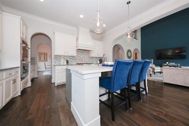 5502 Charlton Ridge Ln, Fulshear, TX 77441 - kitchen with custom range hood, a kitchen bar, backsplash, white cabinetry, and recessed lighting