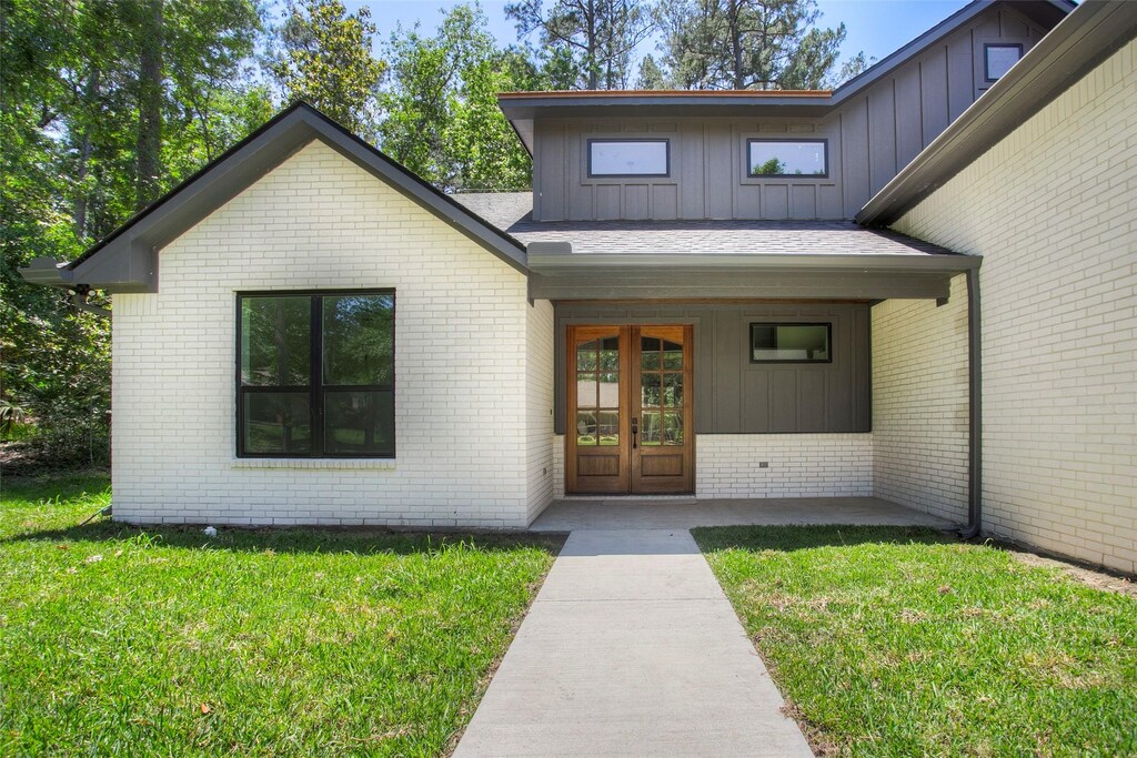1973 Greentree Dr, Huntsville, TX 77340 - entrance to property with board and batten siding, a yard, brick siding, and covered porch