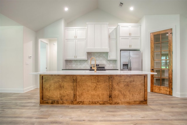 1973 Greentree Dr, Huntsville, TX 77340 - kitchen with stainless steel refrigerator with ice dispenser, a center island with sink, vaulted ceiling, backsplash, and light wood-type flooring