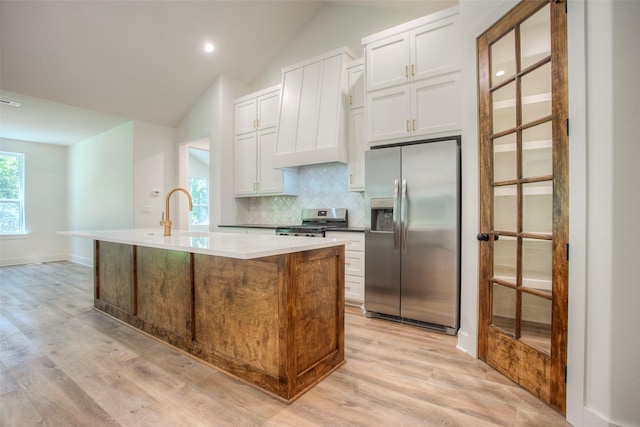 1973 Greentree Dr, Huntsville, TX 77340 - kitchen with appliances with stainless steel finishes, light wood finished floors, tasteful backsplash, vaulted ceiling, and a center island with sink