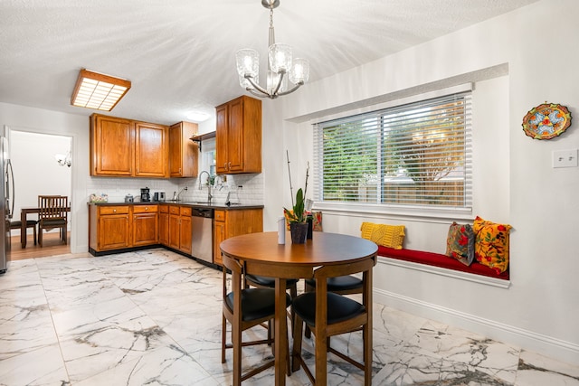 12114 Paddock Way, Houston, TX 77065 - kitchen featuring a chandelier, light marble finish flooring, appliances with stainless steel finishes, brown cabinets, and dark countertops