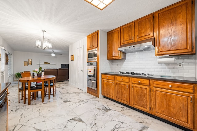12114 Paddock Way, Houston, TX 77065 - kitchen with under cabinet range hood, stainless steel appliances, a warming drawer, a chandelier, and brown cabinets