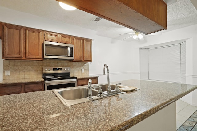 1926 Klauke Ct, Rosenberg, TX 77471 - kitchen featuring stainless steel appliances, decorative backsplash, brown cabinets, and a ceiling fan