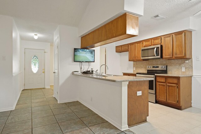 1926 Klauke Ct, Rosenberg, TX 77471 - kitchen featuring stainless steel appliances, a peninsula, tasteful backsplash, and light tile patterned floors