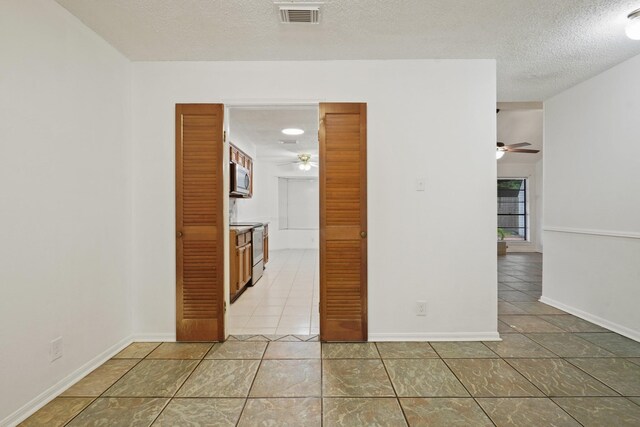 1926 Klauke Ct, Rosenberg, TX 77471 - unfurnished room with a ceiling fan, light tile patterned floors, a textured ceiling, and baseboards