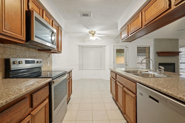 1926 Klauke Ct, Rosenberg, TX 77471 - kitchen featuring stainless steel appliances, a sink, a ceiling fan, brown cabinets, and tasteful backsplash